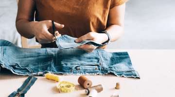 person cutting denim jeans fabric 