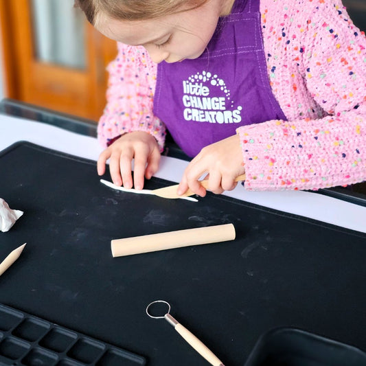 A child uses clay with tools on a silicone craft mat.