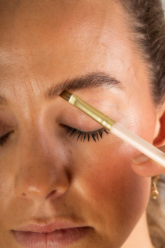 Scoop Whole Beauty model applies natural brow balm to eyebrows using vegan brush