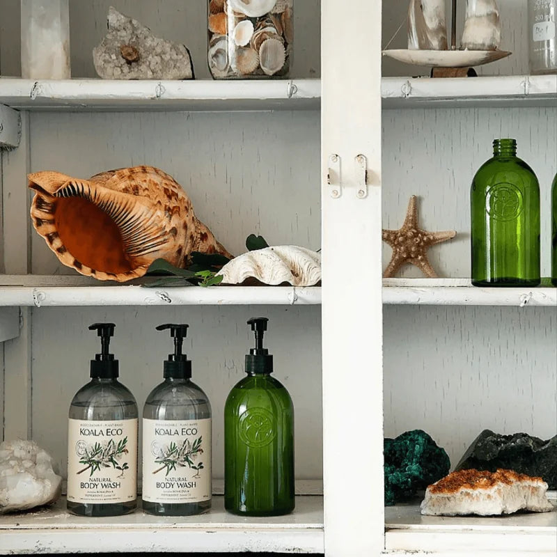 Assortment of natural and organic body wash pump bottles on a bathroom cabinet shelf | us and the earth