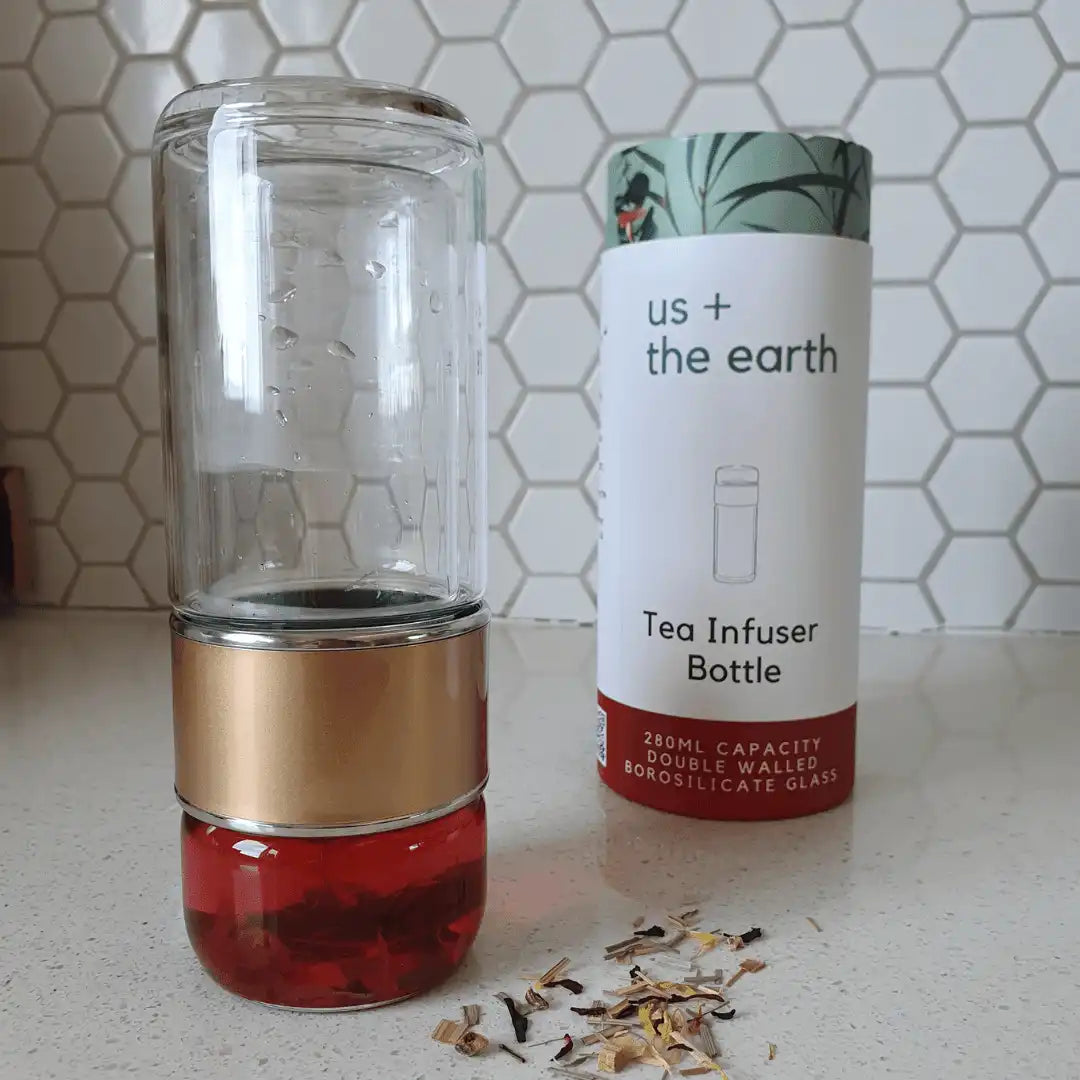 Double wall glass tea infusing bottle placed upside down next to its branded box.