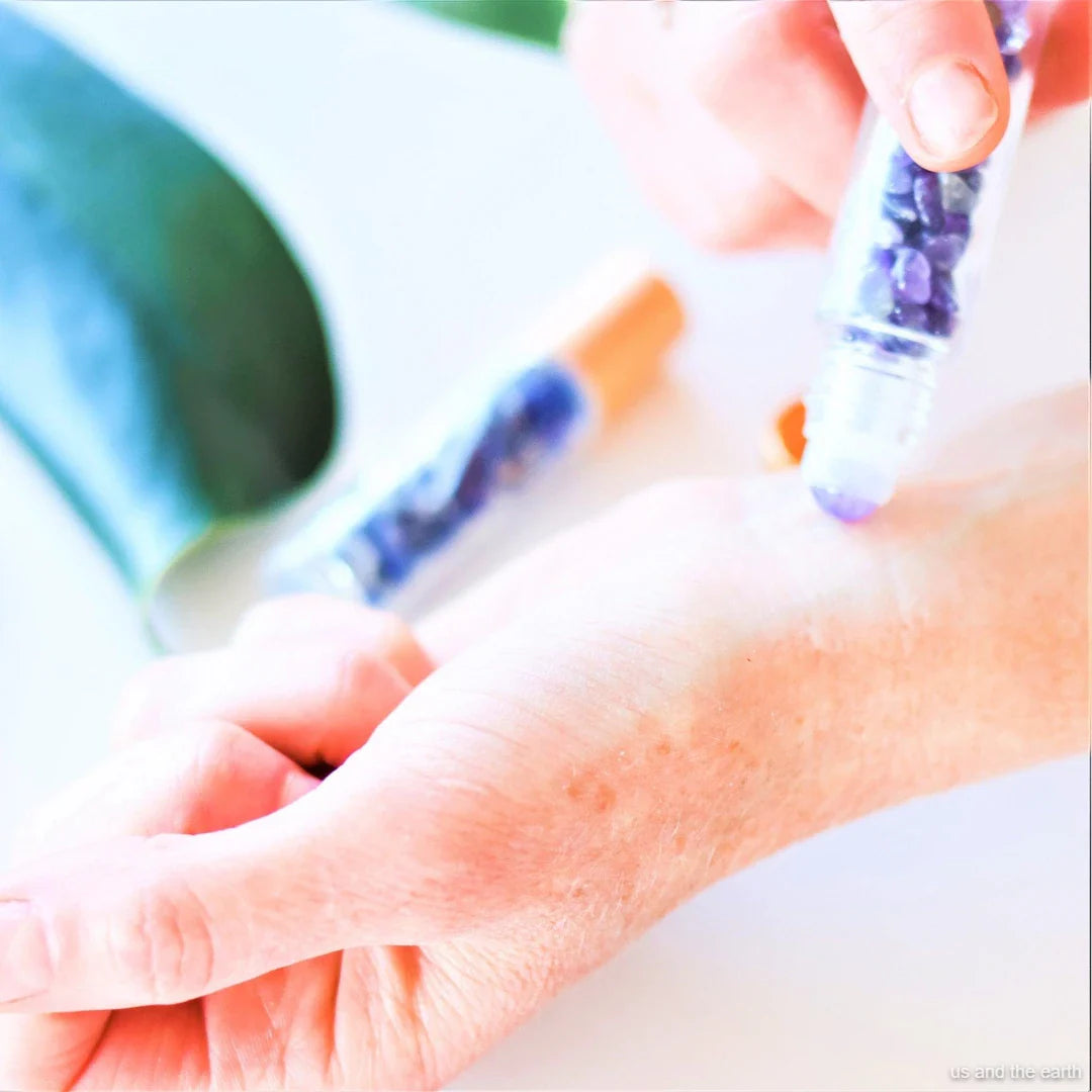 An image featuring a 10ml essential oil crystal gemstone roller bottle being rubbed on a hand, part of the Eco Lifestyle collection from - Us and The Earth.